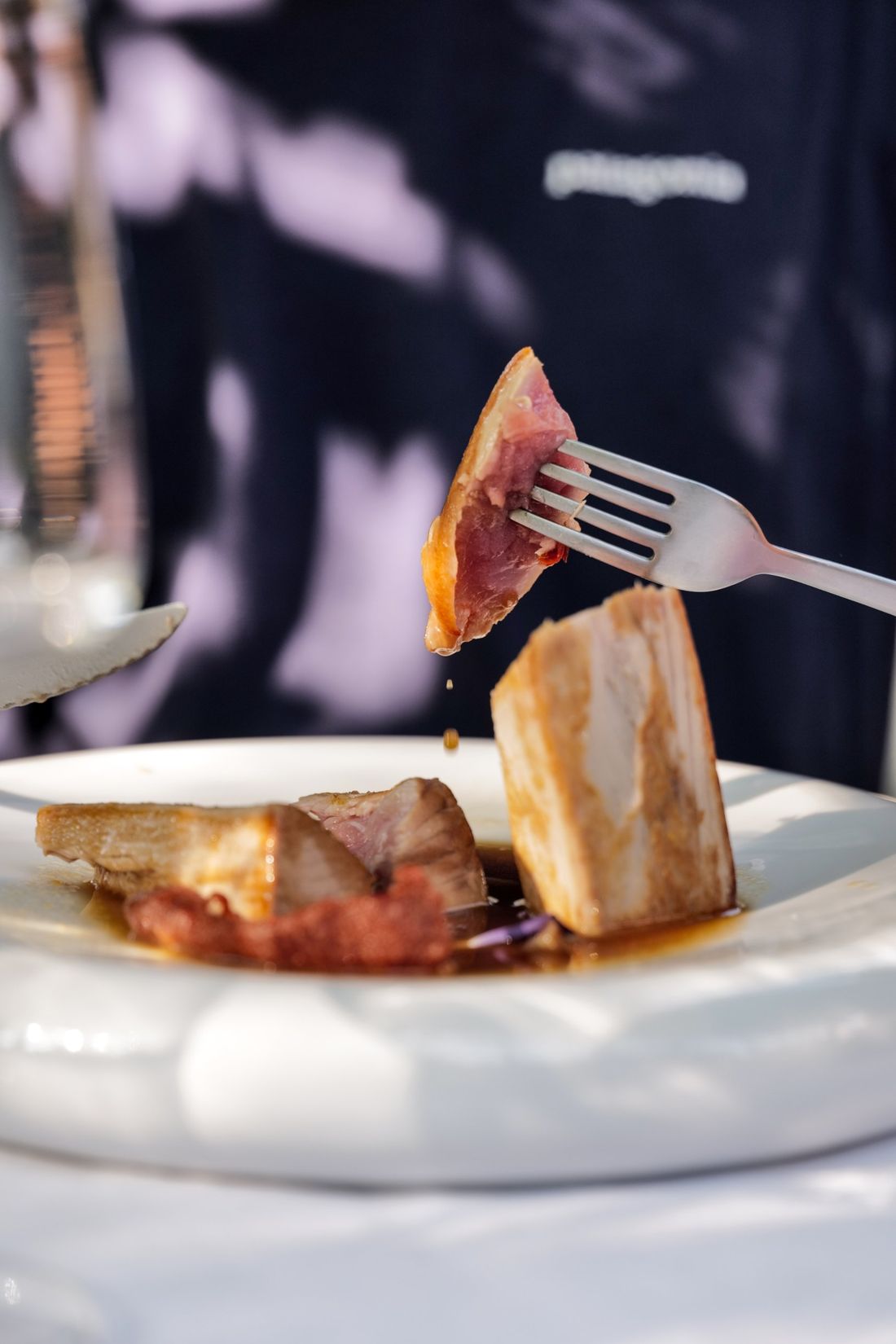 Un boccone di carne glassata sollevato con la forchetta sopra il piatto